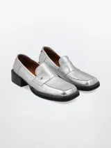 Mocasín plateado de cuero con punta cuadrada, detalle de estrella y talón en rojo.