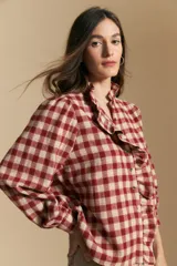 Camisa de algodón a cuadros en tonos rojo y beige, con diseño de volados frontales, cuello alto y mangas largas con leve volumen.