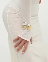 Pulsera rígida de aleación de metales bañada en plata, con diseño abierto y una gota en cada extremo.