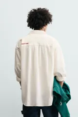 Camisa de corte relajado confeccionada en tejido con mezcla de lino. Presenta cuello solapa, manga larga con puños abotonados, bolsillo plastrón en el pecho y cierre frontal con botones. Incluye bordados a contraste en la espalda.