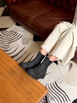 Bota tipo chelsea de cuero negro, con paneles elásticos laterales y suela track dentada.