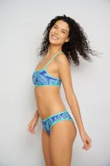 Conjunto de bikini azul con estampado de hojas y ribetes verde agua. El corpiño es tipo top deportivo con tirantes finos y la bombacha es de corte clásico.