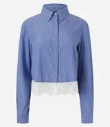 Camisa cropped azul con rayas diplomáticas blancas, cuello clásico, mangas largas y detalle de encaje blanco aplicado en el borde inferior.