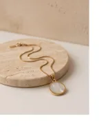 Collar de acero con baño de oro y cadena fina de eslabones, con un dije circular dorado que presenta una imagen en relieve de la Virgen sobre fondo de nácar.