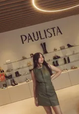 Vestido corto verde de cuero sintético, sin mangas, con cierre frontal de cremallera y cinturón con hebilla.