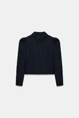 Blazer corta de color azul marino, con cuello solapa y cierre frontal con botones. Cuenta con manga larga con frunces en los hombros.
