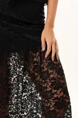 Pollera larga de encaje negro con diseño asimétrico. Presenta un forro interno hasta la altura del muslo y una sección inferior con transparencias que aporta movimiento y fluidez.