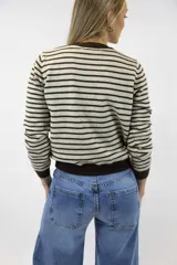 Buzo de punto fino con diseño de rayas horizontales en negro y blanco, cuello redondo, mangas largas y puños y ruedo en tono liso.