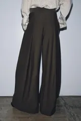 Pantalón de tiro medio color beige perteneciente a la colección ZW Collection, de corte ancho y recto, con detalle de pliegues frontales y cierre con cremallera y ganchos metálicos.