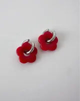 Aros de acero quirúrgico con argolla plateada y dije de flor translúcida en color lila con lunares negros.