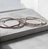 Set de pulseras elásticas compuestas por hileras de strass en tonos rojo, plateado y rosado.