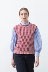 Chaleco tejido de algodón y acrílico, color rojo y blanco con patrón geométrico. Tiene cuello redondo y bordes acanalados en rojo.