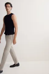 Pantalón de vestir color beige, corte slim fit, con pliegues, bolsillos laterales y traseros ribeteados con botón.