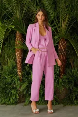 Pantalón de vestir rosado con corte recto, tiro alto y detalle de cadena dorada en la cintura.