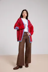 Pantalón de jean color marrón con diseño de paneles laterales estampados con motivos florales. Presenta un corte recto y holgado, con tiro medio y cierre frontal.