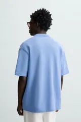 Cárdigan celeste de tejido de algodón con estructura tipo waffle. Tiene cuello solapa, manga corta y cierre frontal con botones.