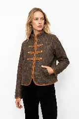 Chaqueta de paño de lana con diseño estilo militar, color marrón. Presenta cierre frontal con apliques tipo alamares y detalles de vivos en cuero en bordes, cuello y puños.