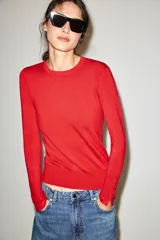 Sweater de punto liso color rojo, con cuello redondo, manga larga y detalles de botones dorados en los puños.