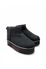 Pantubota corta de gamuza color negro, con plataforma gruesa y suela dentada. Cuenta con presilla en el talón para facilitar el calce.