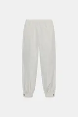 Pantalón bombacho de tiro medio con cintura elástica, confeccionado en tejido de nylon con estampado de cuadros pequeños en blanco y negro. El bajo es elástico con abertura y botón a presión.