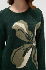 Sweater de punto jacquard con diseño floral abstracto en tonos tierra sobre fondo negro, de corte holgado, cuello redondo y manga larga.