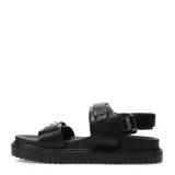 Sandalias de plataforma plana Miss Carol modelo Naira, color negro con doble tira ajustable con hebillas metálicas plateadas y suela dentada.