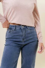 Pantalón de jean estilo wide leg, color celeste claro, con tiro medio, cinco bolsillos y cierre frontal con botón y cremallera.