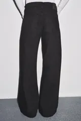 Jeans de tiro bajo, pierna ancha y largo completo, color negro. Presenta cinco bolsillos y cierre frontal con cremallera y botón metálico.