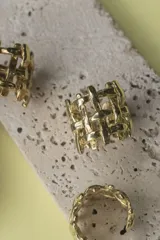 Anillo de diseño abierto con estructura de rejilla entrelazada, elaborado artesanalmente en metal con acabado plateado.