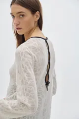 Túnica tipo vestido color crudo, tejido calado, largo midi y cortes a los lados. Tiene cuello redondo y mangas largas.