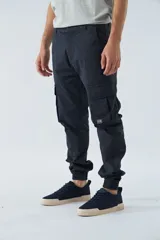 Pantalón cargo color beige, corte slim, con bolsillos laterales con botón, cierre con botón y puños en los tobillos.