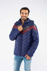 Campera puffer de nylon con relleno de guata, diseño capitoneado y capucha desmontable. Presenta un patrón de chevron en color azul sobre base negra, cierre frontal y bolsillos laterales con cierre.