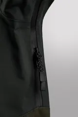 Cazadora deportiva de esquí con diseño bicolor en tonos negro y verde oliva. Presenta capucha amplia con visera, cierre frontal con cremallera termosellada, bolsillos frontales y en manga con cierres impermeables, y aberturas de ventilación en las axilas. Incluye faldón interior antinieve, puños ajustables y tecnología de rescate RECCO.
