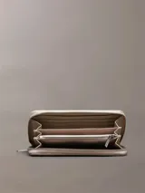 Billetera rectangular Calvin Klein con cierre perimetral de cremallera. Presenta un diseño texturizado con monograma de la marca en relieve y logo metálico en la parte frontal.