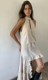 Blusa tipo musculosa de cuello halter con abertura frontal tipo gota, confeccionada en tejido ligero color crudo.