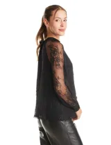 Blusa de encaje negro con cuello halter y mangas largas transparentes. Presenta un diseño elegante con detalles florales en el encaje y cierre con lazo en la espalda.