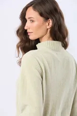 Buzo tejido combinado de color beige, con cuello alto, medio cierre metálico y puños y ruedo acanalados en tono tostado.