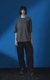 Remera de manga corta con cuello redondo y calce oversize, color gris oscuro. Presenta una estampa frontal con diseño gráfico de un escorpión y una rosa, junto con texto tipográfico.