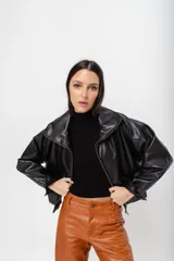 Chaqueta bomber de cuero sintético color negro, con cierre frontal y cuello alto.