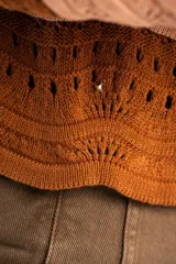 Sweater de tejido de punto con diseño de rayas horizontales onduladas en tonos marrón y beige. Presenta cuello redondo, mangas largas y corte oversize.