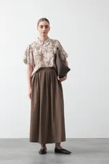 Falda larga plisada color marrón, de silueta amplia y caída fluida.