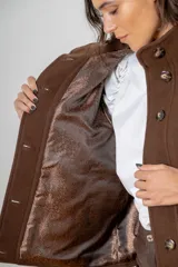Campera de paño de lana color marrón con diseño oversize. Presenta cuello alto, cierre frontal con botones y detalles en pana azul marino en los puños y en las tapas de los bolsillos frontales.