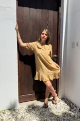 Vestido corto color beige de voile de rayon, con cuello bebé con volados y mangas cortas abullonadas.