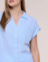 Camisa de lino de estructura recta, color beige con rayas verticales blancas. Cuenta con cuello solapa, escote en V abierto, abotonadura frontal, bolsillo plaqué en el pecho, mangas cortas de hombro caído y ruedo recto.