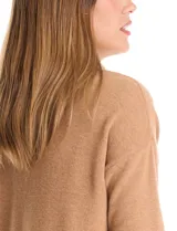 Buzo de tejido suave con cuello volcado ajustable mediante cordones con punteras metálicas. Presenta mangas largas con puños decorados con botones metálicos, hombros caídos y ruedo redondeado con aberturas laterales.