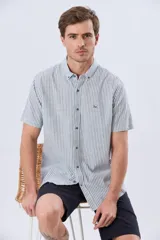 Camisa de manga corta confeccionada en mezcla de lino y algodón, con diseño de rayas verticales en tonos celeste y blanco. Cuenta con cuello camisero, botonadura frontal y bordado sutil en el pecho.