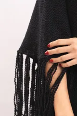 Triángulo tejido artesanalmente en telar manual con hilado mecha de lana merino, de color negro, con diseño envolvente y flecos largos en los bordes.