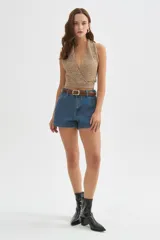 Top de punto con lentejuelas en tonos beige y dorado, con escote halter cruzado en V, sin mangas y corte corto.
