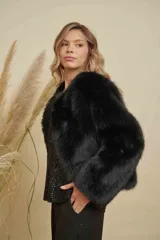 Abrigo corto de piel sintética en color negro, con diseño de manga larga y corte holgado.