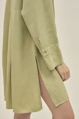 Camisola color verde pistacho, de corte holgado, confeccionada en lino y tencel. Tiene cuello camisero, mangas largas con puños abotonados, cierre frontal con botones y bolsillos laterales.